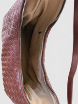 Close-up of an open brown woven leather shoulder bag showing the beige interior lining and silver zipper.
