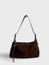 A dark brown faux suede hobo shoulder bag with a matching braided leather tassel charm, shown against a light gray studio background.